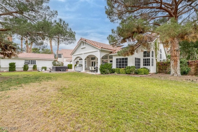 rear view of property with a patio area, a hot tub, and a yard