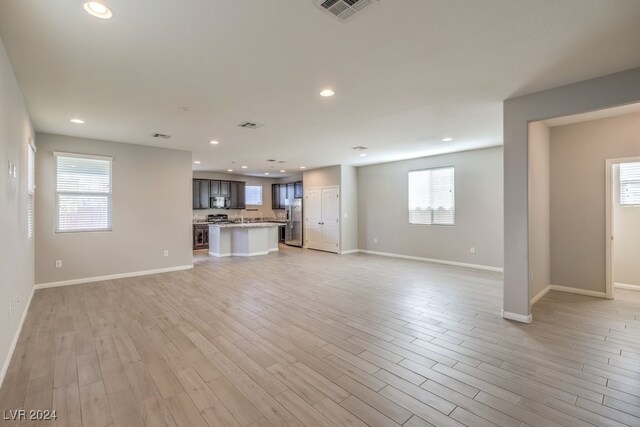 unfurnished living room with light hardwood / wood-style flooring and a healthy amount of sunlight