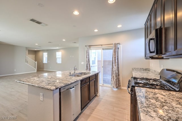 kitchen featuring sink, an island with sink, stainless steel appliances, and light hardwood / wood-style flooring