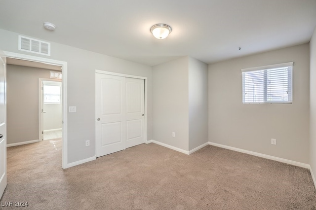 unfurnished bedroom with multiple windows, a closet, and light colored carpet