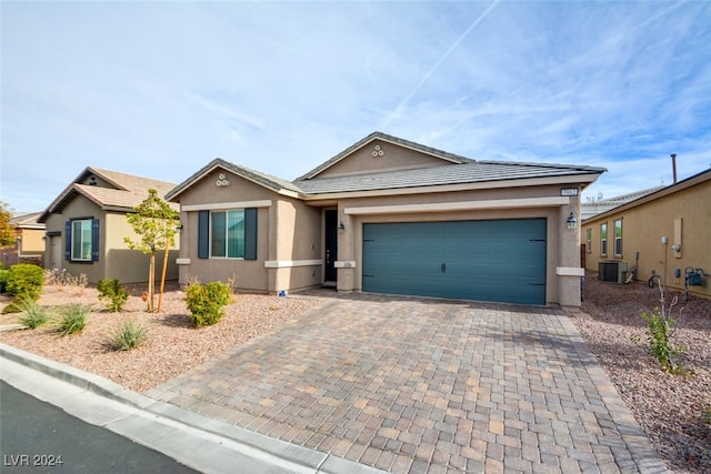 single story home featuring central AC unit and a garage