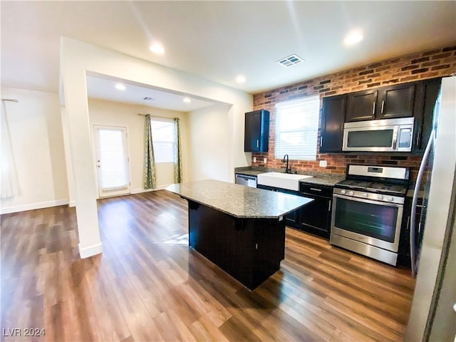 kitchen featuring a wealth of natural light, a center island, stainless steel appliances, and sink