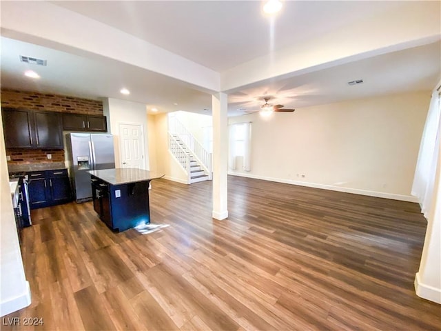 kitchen featuring a center island, tasteful backsplash, dark hardwood / wood-style floors, stainless steel fridge, and a breakfast bar area