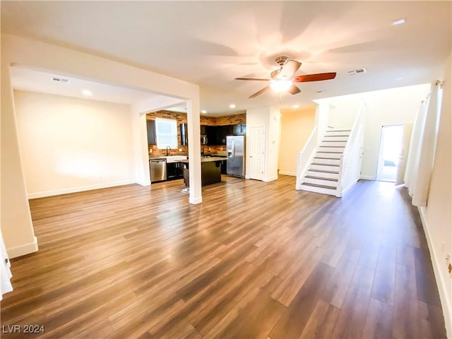 unfurnished living room with hardwood / wood-style floors, ceiling fan, and sink