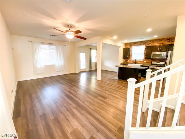 unfurnished living room featuring ceiling fan, dark hardwood / wood-style flooring, and sink