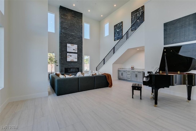 living room featuring a stone fireplace and a high ceiling