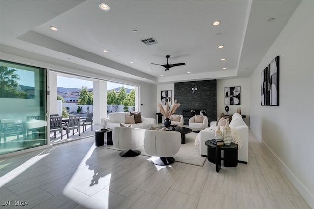 living room with ceiling fan and a raised ceiling