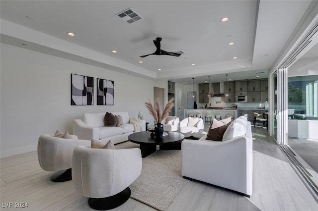 living room with a tray ceiling and ceiling fan