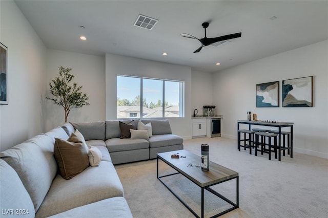 living room with light carpet, sink, ceiling fan, and beverage cooler