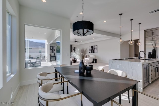 dining space featuring ceiling fan, light wood-type flooring, and sink