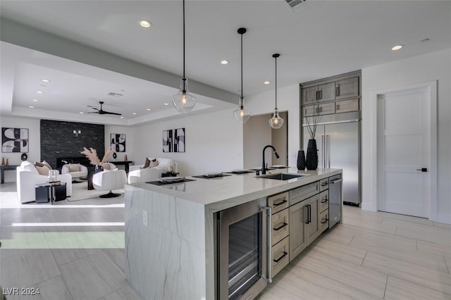 kitchen with ceiling fan, sink, beverage cooler, pendant lighting, and a spacious island