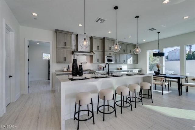 kitchen with a large island with sink, a kitchen breakfast bar, and hanging light fixtures