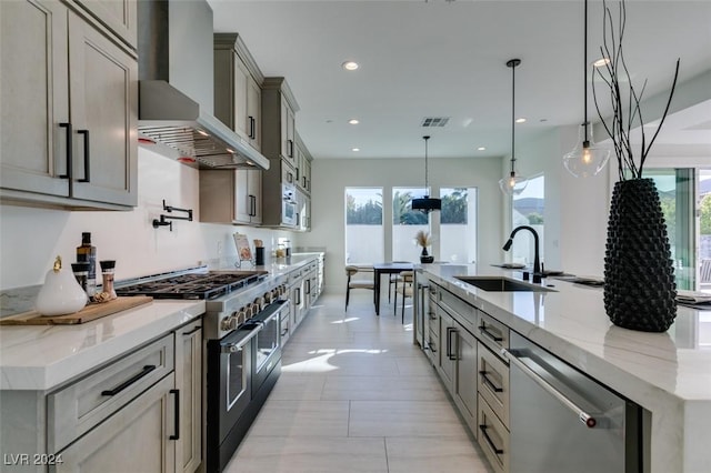 kitchen with a large island, sink, stainless steel appliances, wall chimney range hood, and pendant lighting