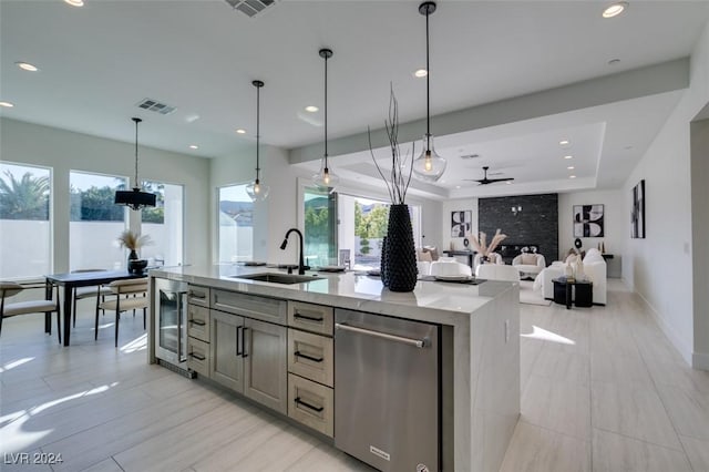 kitchen featuring ceiling fan, sink, dishwasher, pendant lighting, and a kitchen island with sink