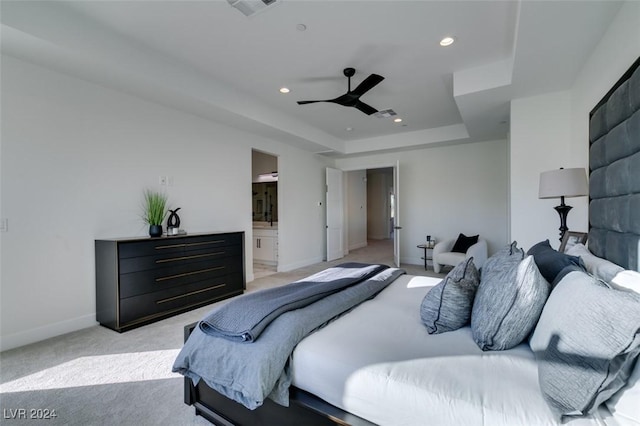 bedroom with a raised ceiling, ensuite bath, ceiling fan, and light colored carpet