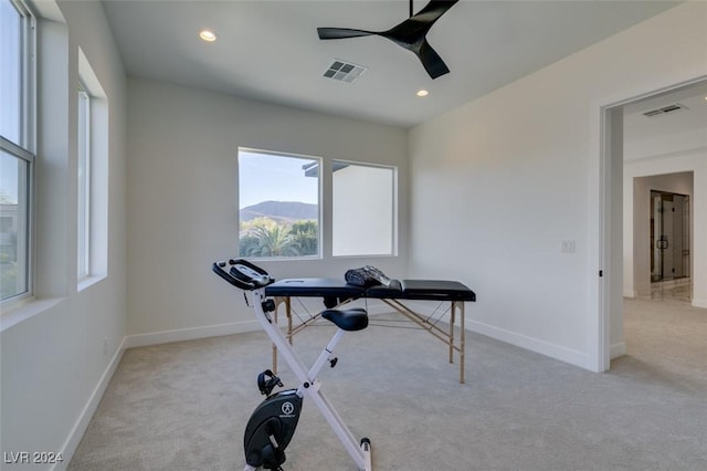 workout room with ceiling fan and light colored carpet