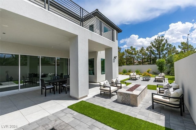 view of patio featuring a balcony and an outdoor living space with a fire pit