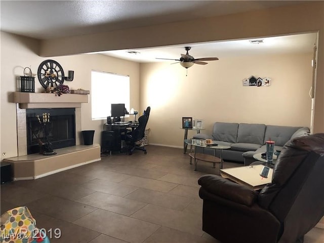 living room with ceiling fan, a fireplace, and dark tile patterned floors