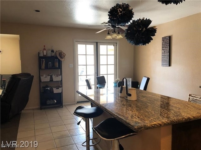 tiled dining space with ceiling fan and a textured ceiling