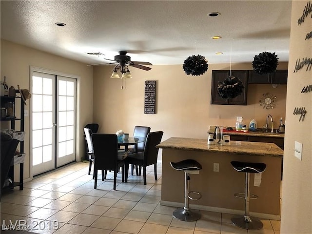 tiled dining space featuring a textured ceiling, ceiling fan, and sink