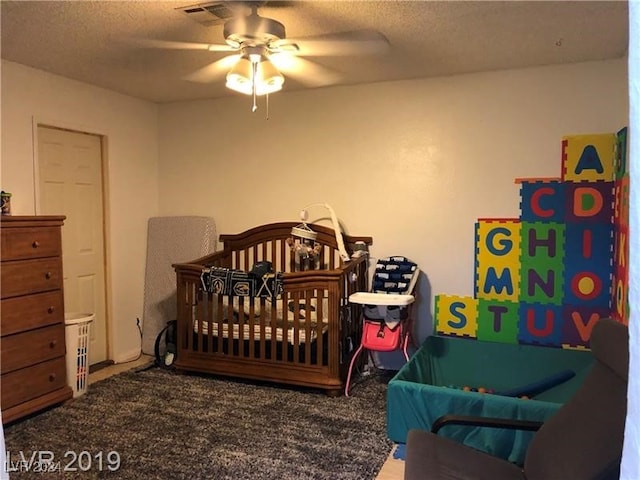 carpeted bedroom with a textured ceiling, ceiling fan, and a crib