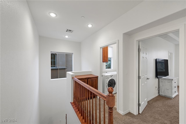 corridor with washer / dryer and light carpet