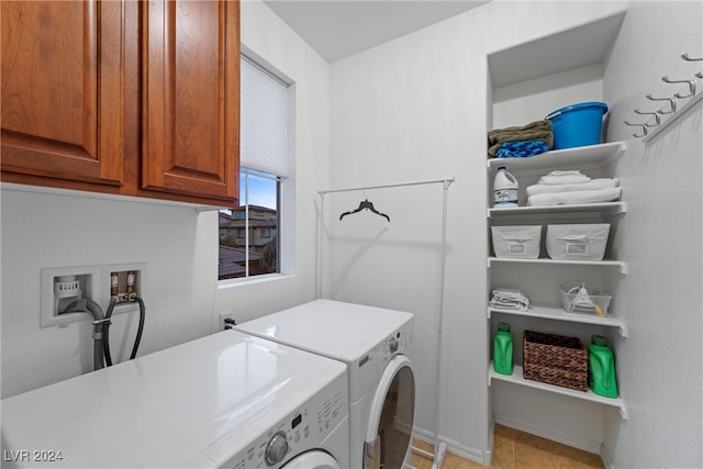 clothes washing area with washer and clothes dryer, light tile patterned floors, and cabinets