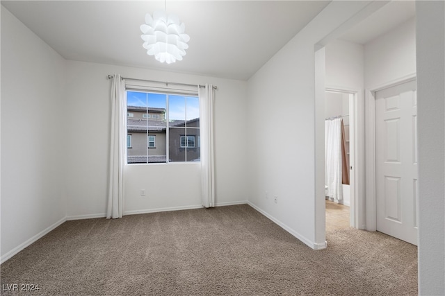 unfurnished room featuring carpet flooring and a notable chandelier