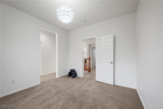 empty room featuring light carpet and a notable chandelier