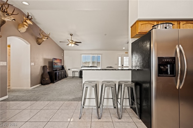 kitchen featuring lofted ceiling, light tile patterned floors, stainless steel refrigerator with ice dispenser, and ceiling fan