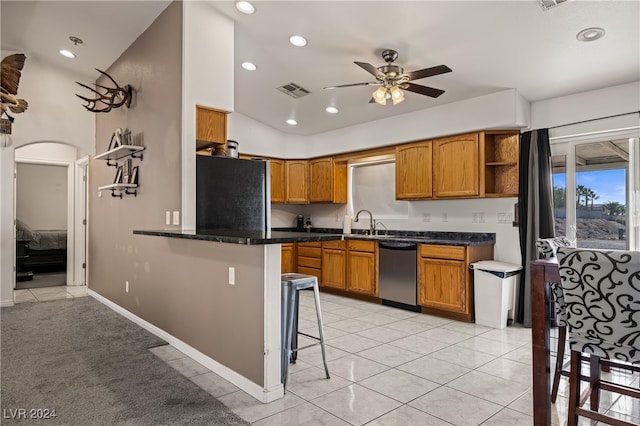 kitchen featuring black fridge, stainless steel dishwasher, ceiling fan, kitchen peninsula, and a breakfast bar area