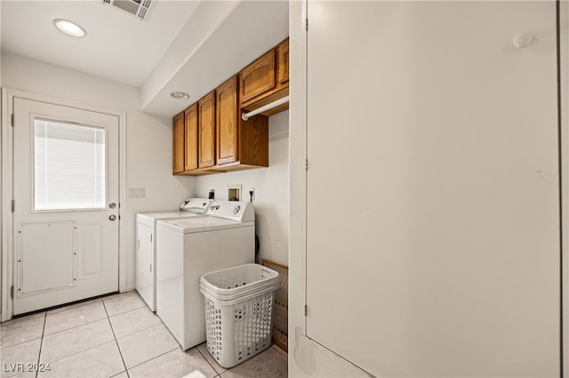 clothes washing area featuring cabinets, light tile patterned floors, and washer and dryer