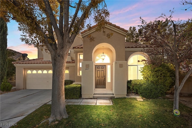 mediterranean / spanish-style house with a garage and a yard