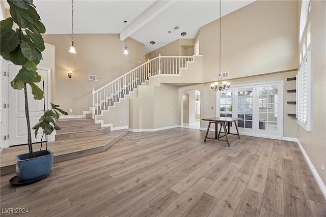 living room featuring beam ceiling, high vaulted ceiling, a notable chandelier, and hardwood / wood-style flooring