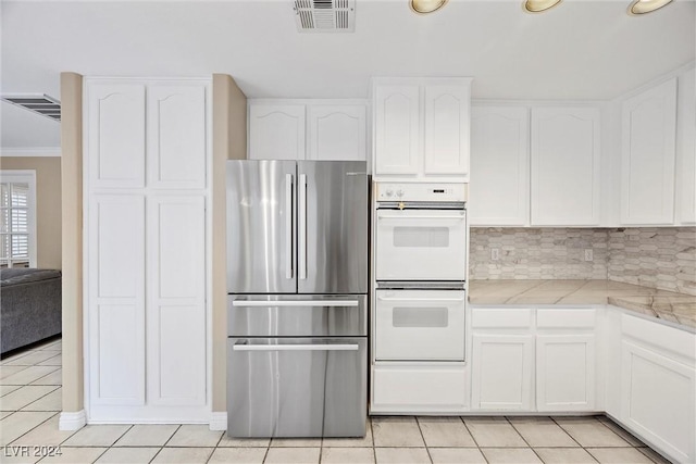 kitchen featuring white cabinets, stainless steel refrigerator, double oven, and light tile patterned flooring