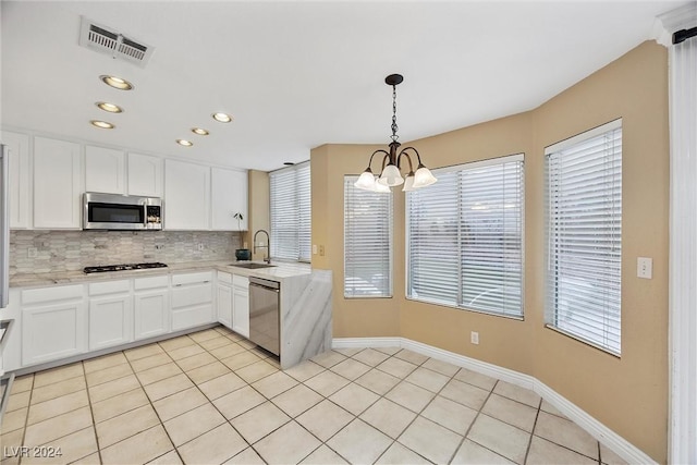 kitchen featuring appliances with stainless steel finishes, white cabinetry, hanging light fixtures, and sink