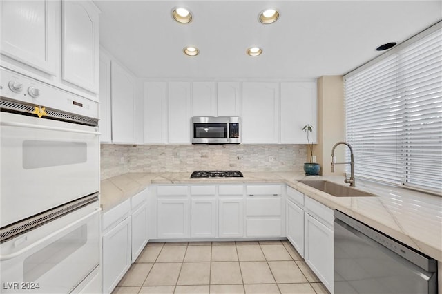 kitchen with sink, white cabinets, stainless steel appliances, and light tile patterned floors