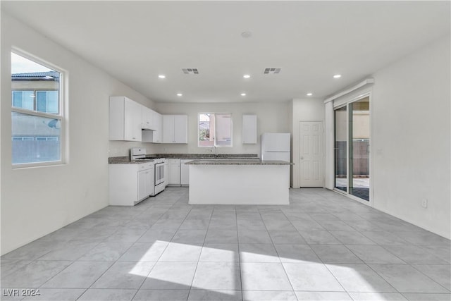 kitchen with white appliances, a center island, white cabinetry, and light tile patterned flooring