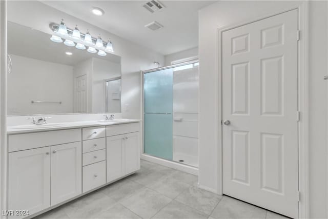 bathroom with tile patterned flooring, vanity, and walk in shower