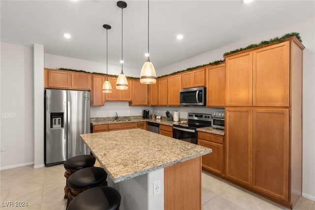 kitchen featuring a breakfast bar, hanging light fixtures, light stone countertops, appliances with stainless steel finishes, and a kitchen island