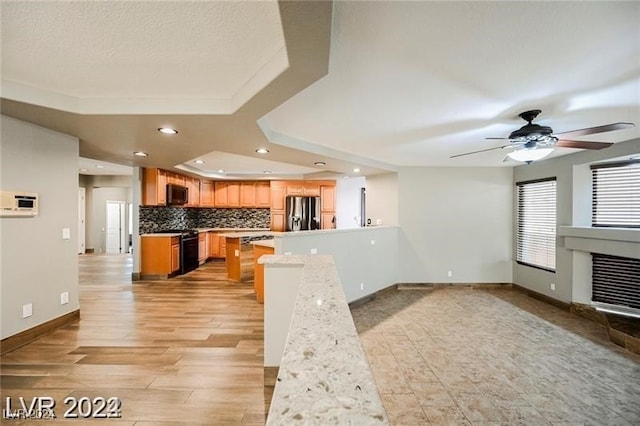 kitchen with a raised ceiling, stainless steel refrigerator with ice dispenser, ceiling fan, decorative backsplash, and light hardwood / wood-style floors