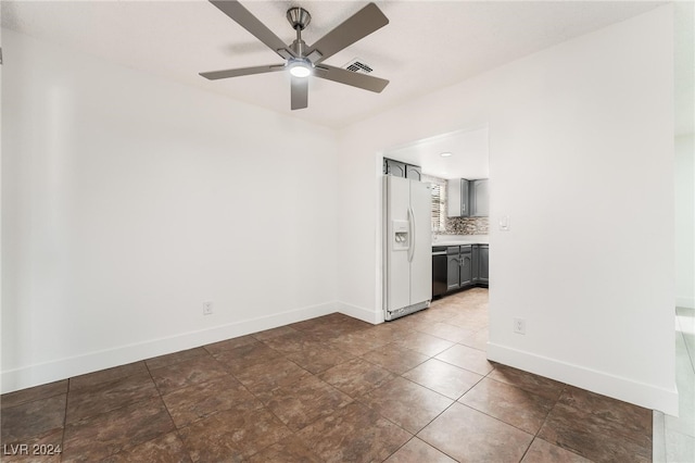 empty room featuring ceiling fan and dark tile patterned floors