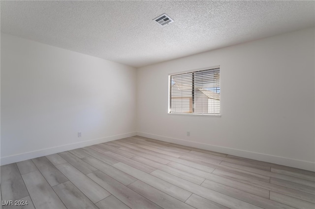 unfurnished room featuring light wood-type flooring and a textured ceiling