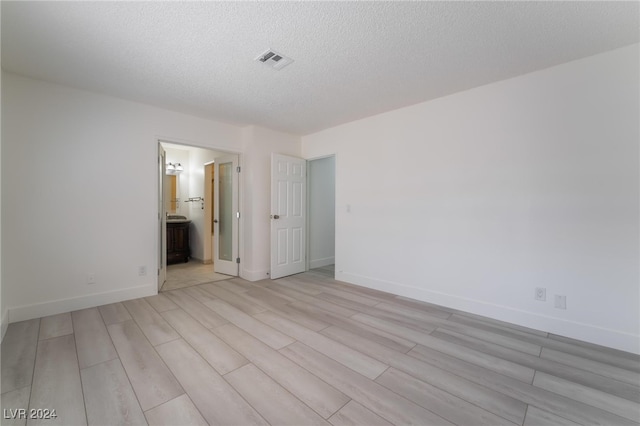 empty room with light hardwood / wood-style floors and a textured ceiling