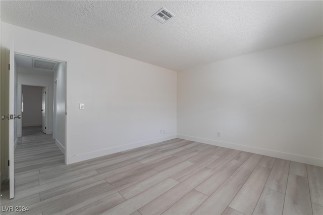 unfurnished room featuring a textured ceiling and light hardwood / wood-style floors