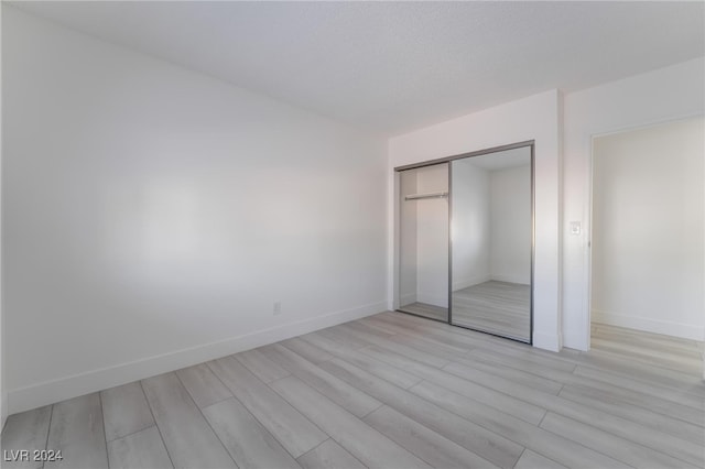 unfurnished bedroom with light wood-type flooring and a closet