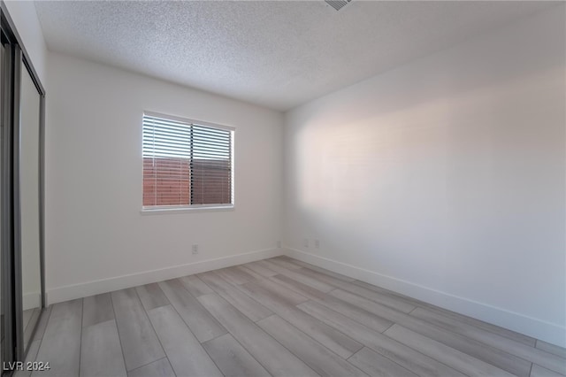 interior space with light wood-type flooring, a textured ceiling, and a closet