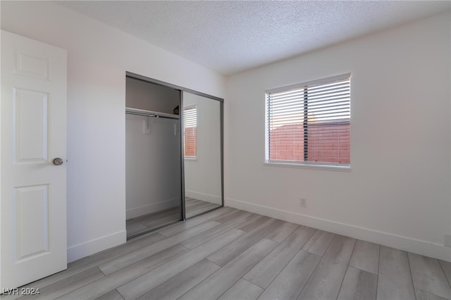 unfurnished bedroom featuring a textured ceiling, light hardwood / wood-style flooring, and a closet