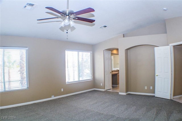 unfurnished bedroom featuring lofted ceiling, connected bathroom, ceiling fan, and carpet