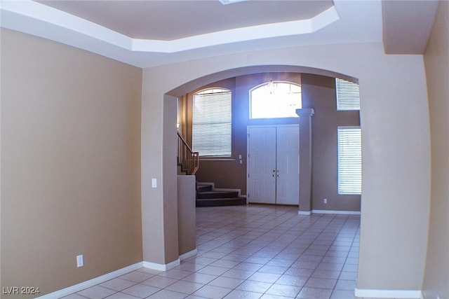 tiled entrance foyer with a tray ceiling